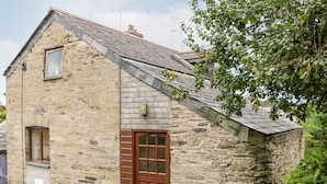 A stone building with a sloped roof, a wooden door, and a small window.