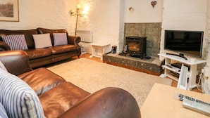 A cozy living room with a brown leather sofa, a white fireplace, and a television on a stand.