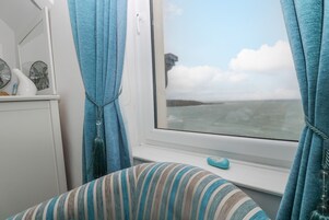 Una habitación con ventana que da a una masa de agua, un cojín a rayas y un objeto decorativo pequeño en el alféizar.