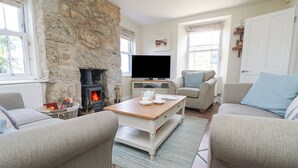 A cozy living room with a stone fireplace, a flat-screen TV, and comfortable seating. - Rose Villa (Penzance)