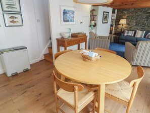 Ein gemütliches Wohnzimmer mit einem runden Holztisch, einem gestreiften Sofa und einer Steinwand.