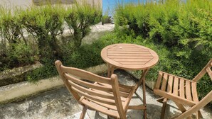 A wooden table and chairs set on a patio with a view of the sea. - Pegs (Helston)