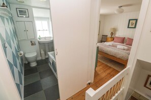 Ein Schlafzimmer mit Bett, Nachttisch, Lampe und Fenster.