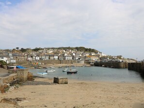 A coastal town with a sandy beach, boats, and a stone wall. - Jubilee Cottage (Penzance)