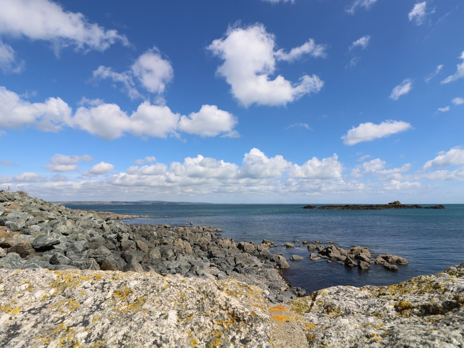 Une côte rocheuse, sous un ciel dégagé et une mer calme.