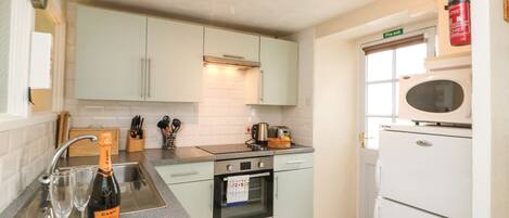 A kitchen with a granite countertop, a sink, a stove, and a microwave.