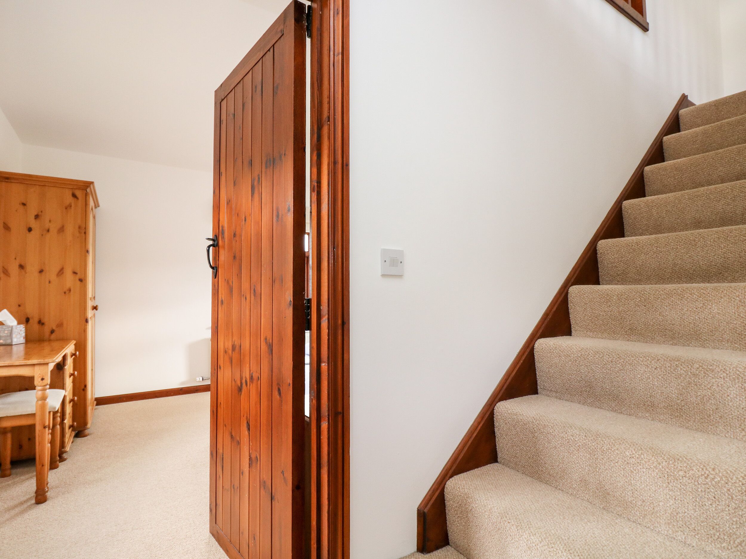 A wooden door, a staircase, and a wooden cabinet with a tissue box.