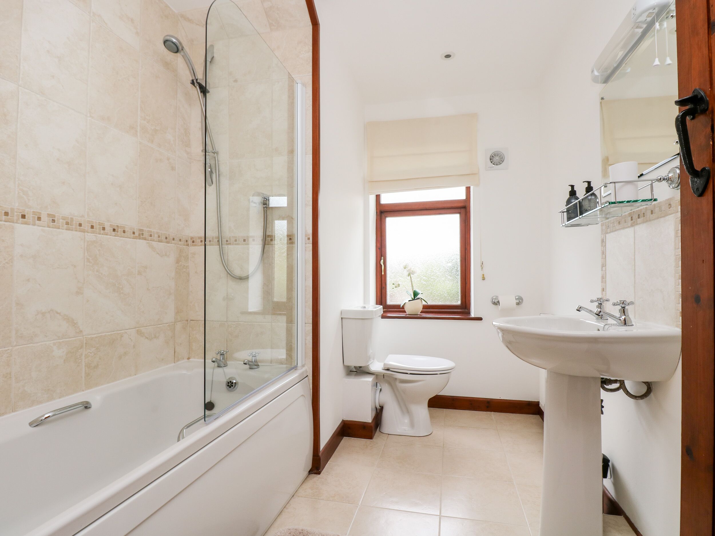 A bathroom with a glass-enclosed shower, a toilet, and a sink.