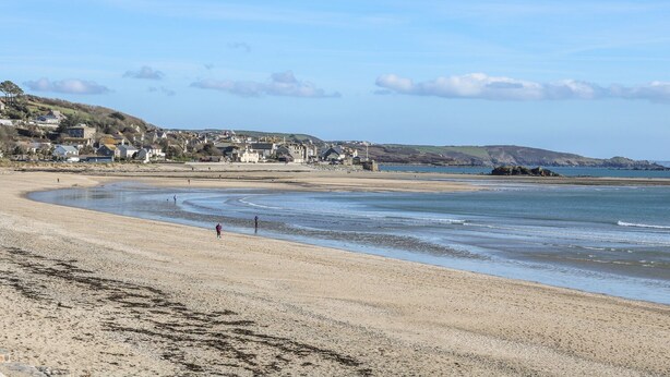Une plage côtière avec des maisons en arrière-plan et un ciel dégagé.