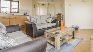 A modern living room with a grey sofa, a wooden coffee table, and a grey armchair. - Shoreline (Penzance)