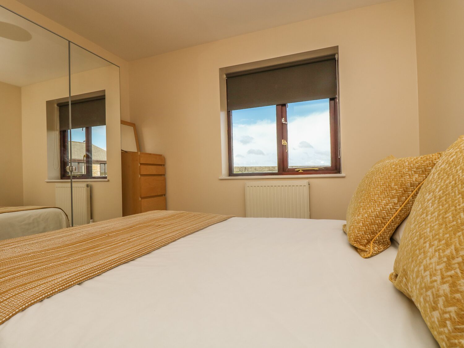 Una camera da letto con un letto, una cassettiera in legno, una finestra vista e un termosifone.