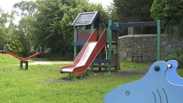 A playground with a red slide, a seesaw, and a climbing structure.