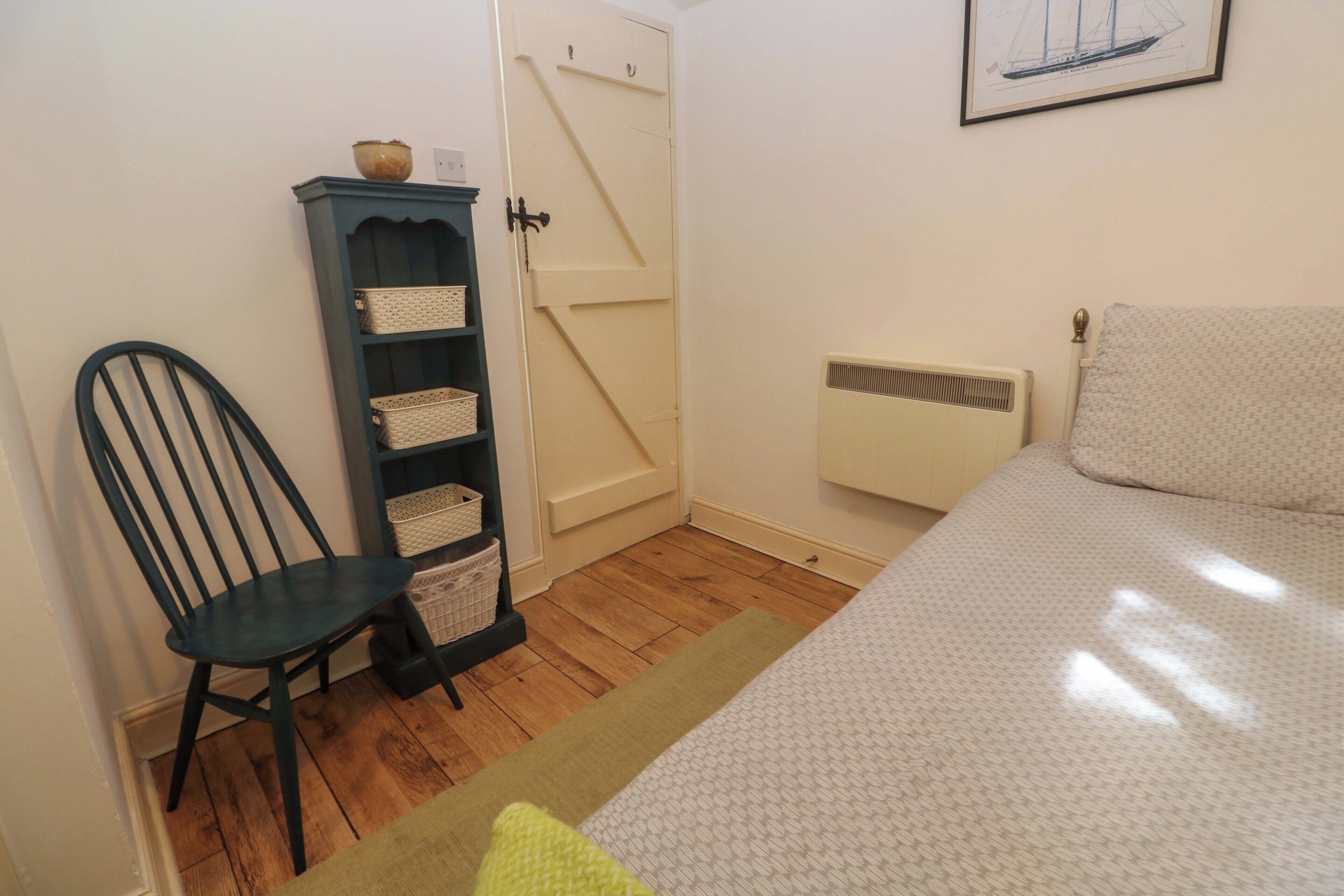 Ein Schlafzimmer mit einem Bett, einem Sessel, einem Schrank und einer Heizung.