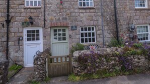 A stone cottage with a white door, a green door, and a sign indicating 'May Cottage.' - May Cottage (St Austell)