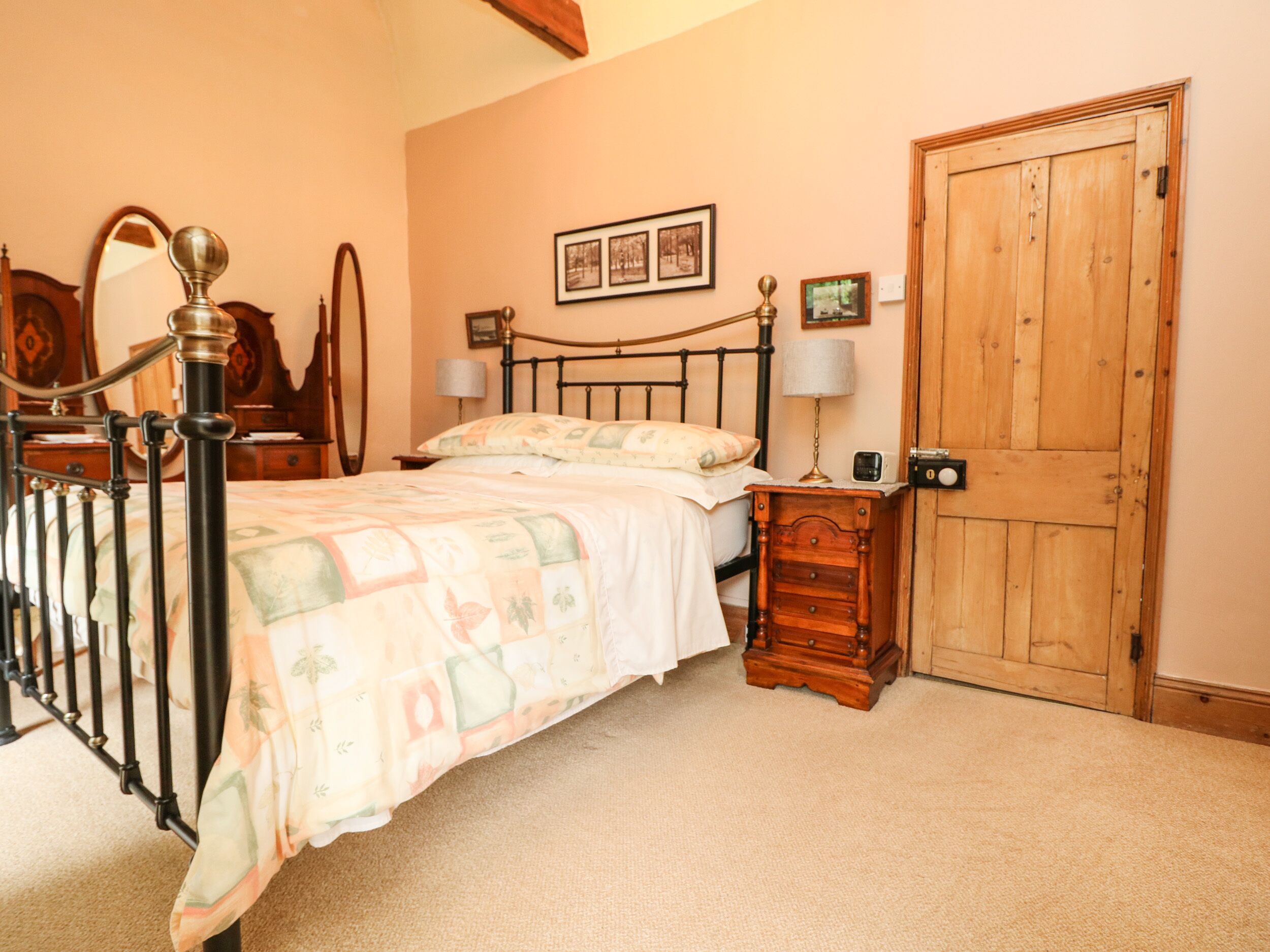 A bedroom with a bed, bedside tables, a wooden wardrobe, and a mirror.