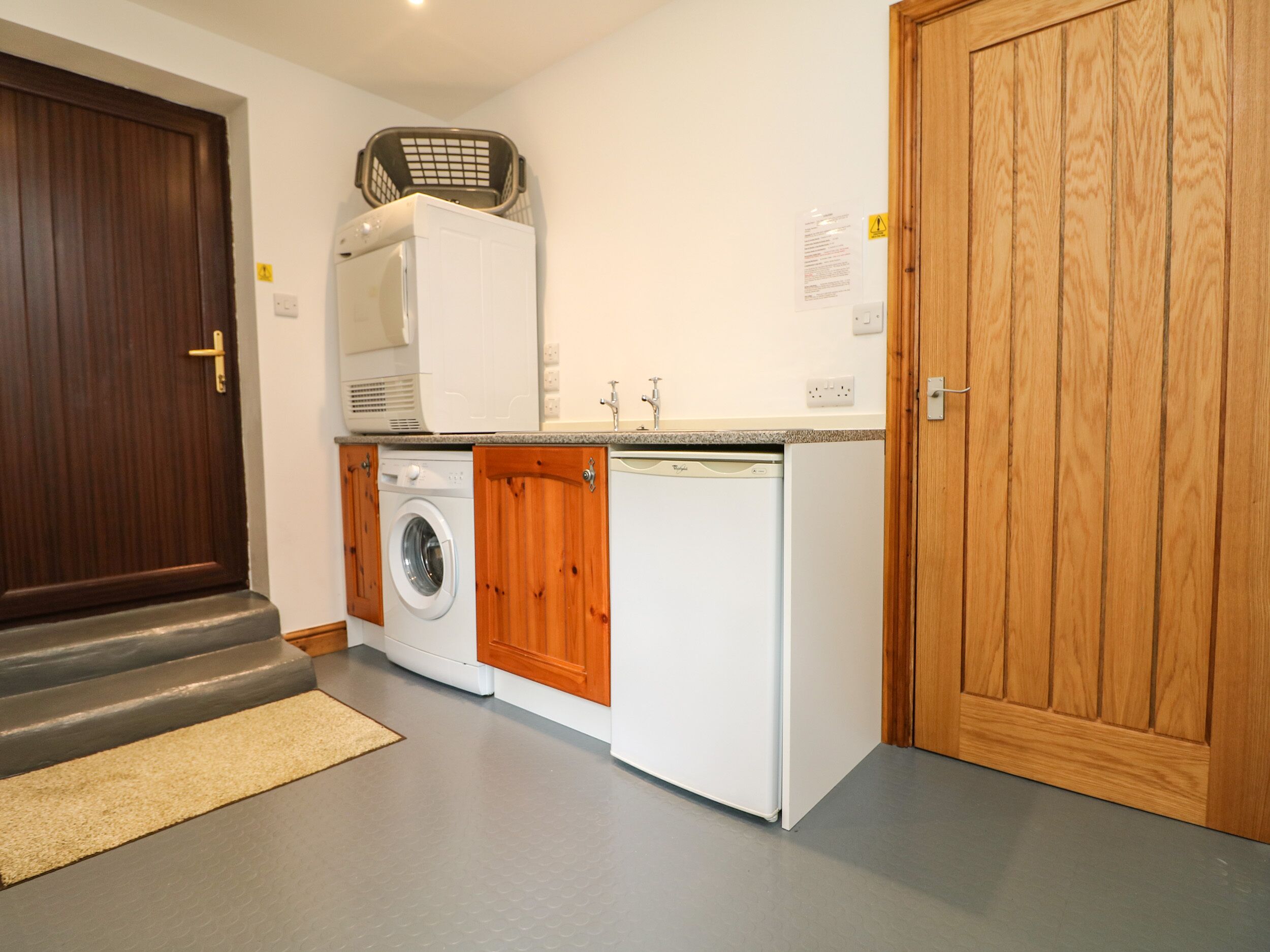 A compact kitchen with a washing machine, a dishwasher, and a wooden cabinet.