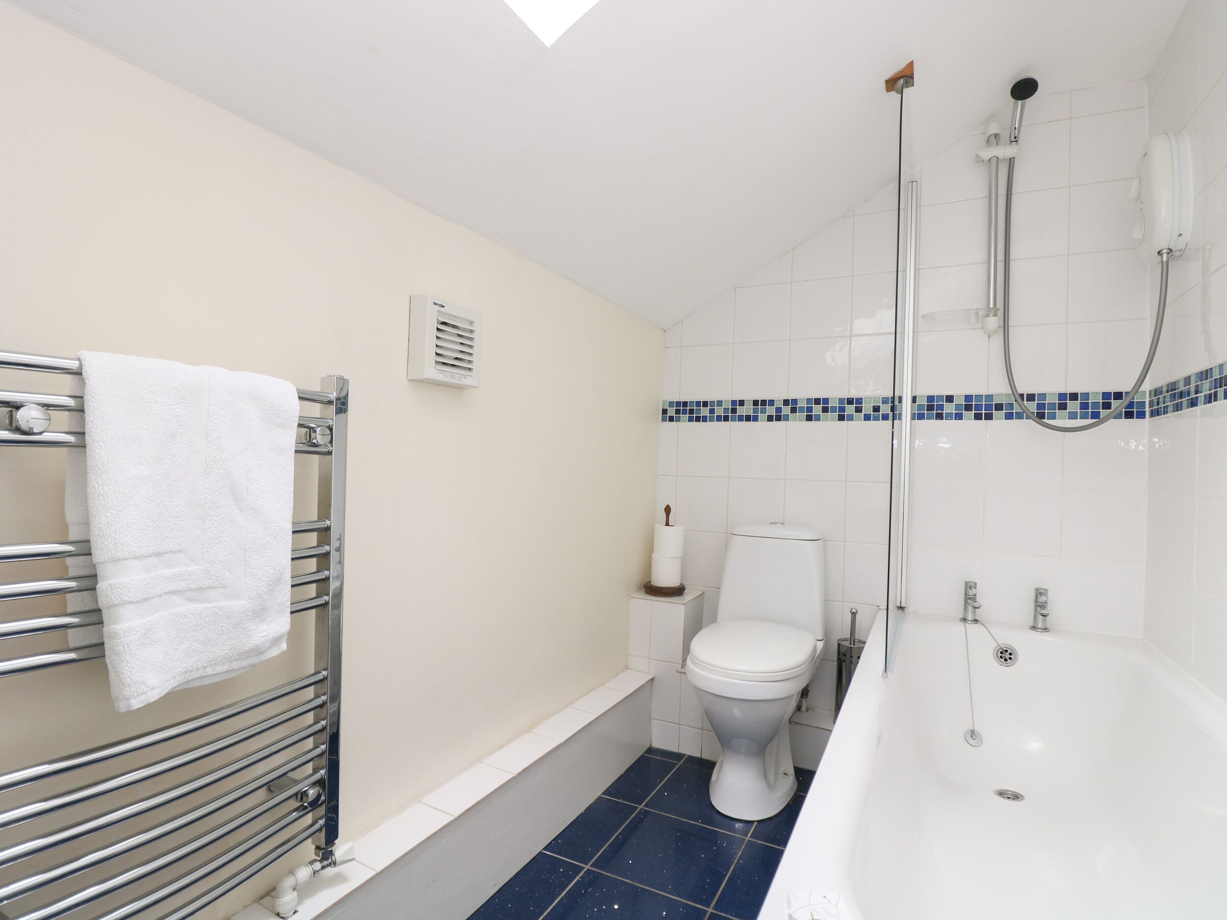 A bathroom with a white bathtub, a toilet, and a shower with a glass door.