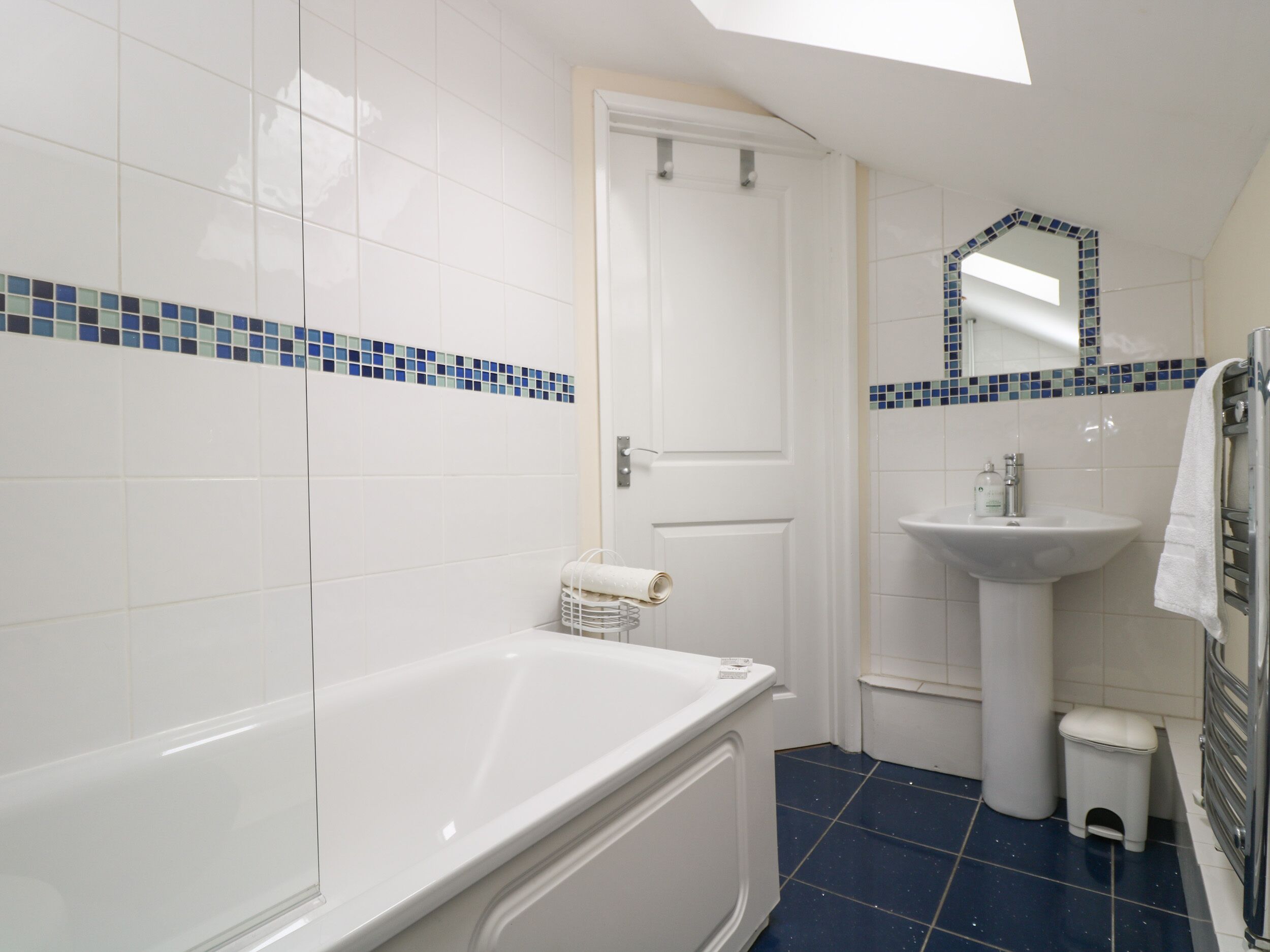 A bathroom with a bathtub, a sink, and a mirror.