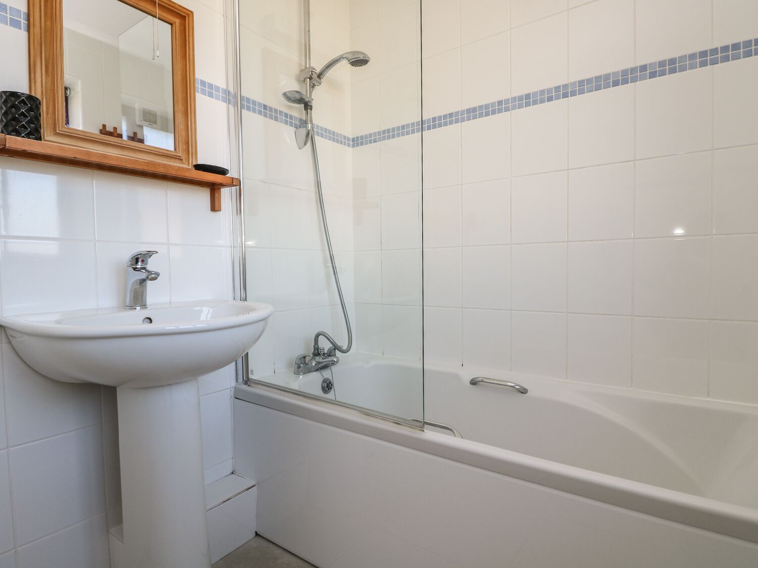 Une salle de bain avec un lavabo blanc, un miroir et une baignoire.
