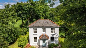 A white house with a red roof surrounded by lush greenery. - Penwarne Lodge (Falmouth)