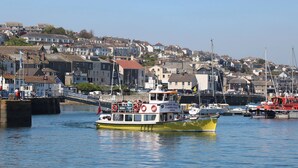 A ferry boat docked at a harbor with houses in the background. - Penwarne Lodge (Falmouth)