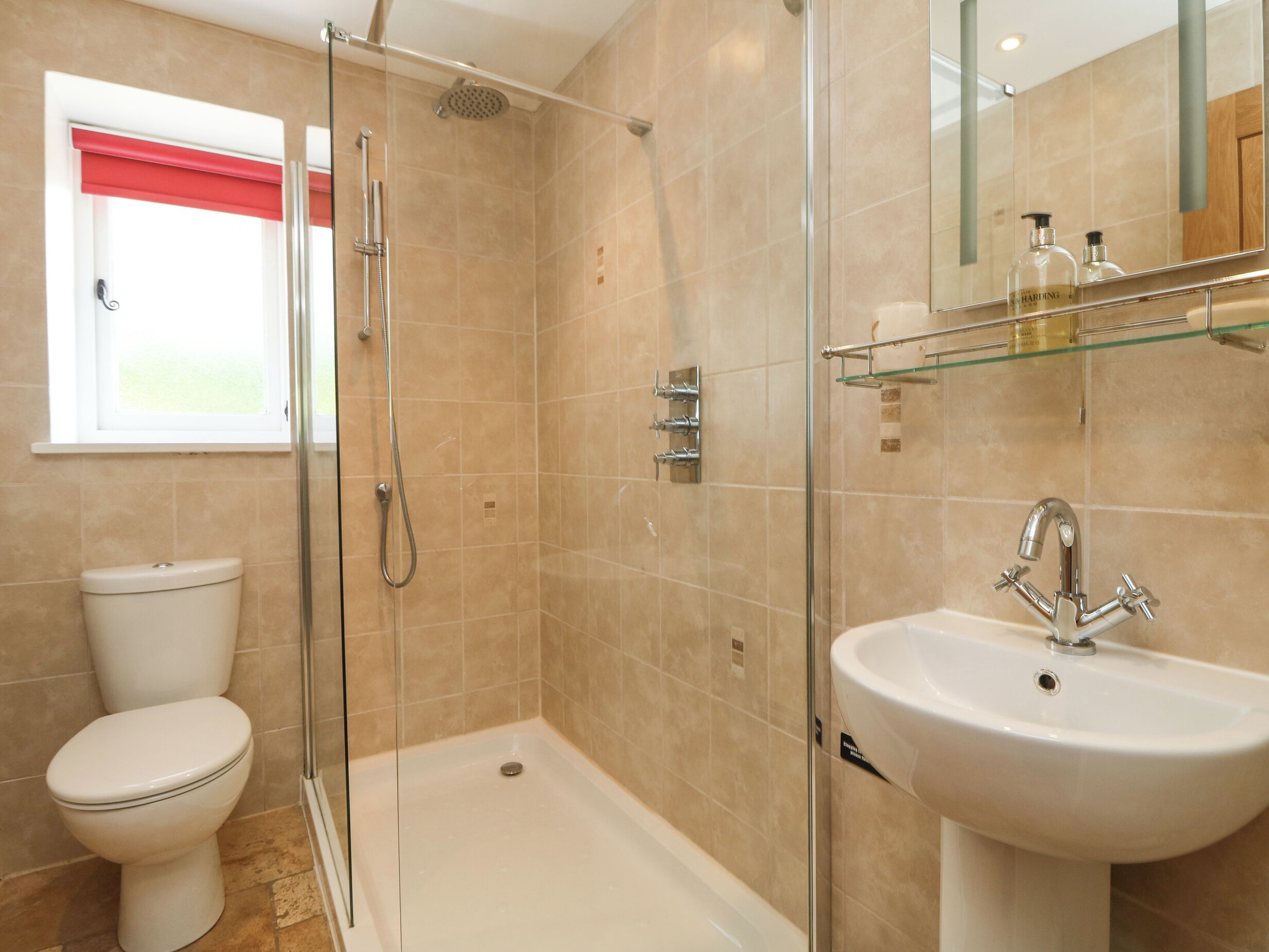 A bathroom with a glass-enclosed shower, a toilet, and a sink.