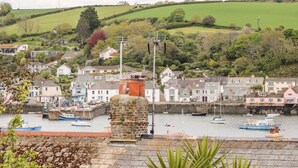 A coastal town with a harbor, stone buildings, and green hills in the background. - Seabien (Falmouth)