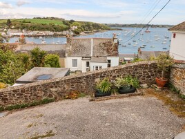 A coastal town with stone buildings, a harbor with boats, and a view of the sea.
