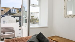 Une pièce avec un lit, un banc, une fenêtre et un miroir.