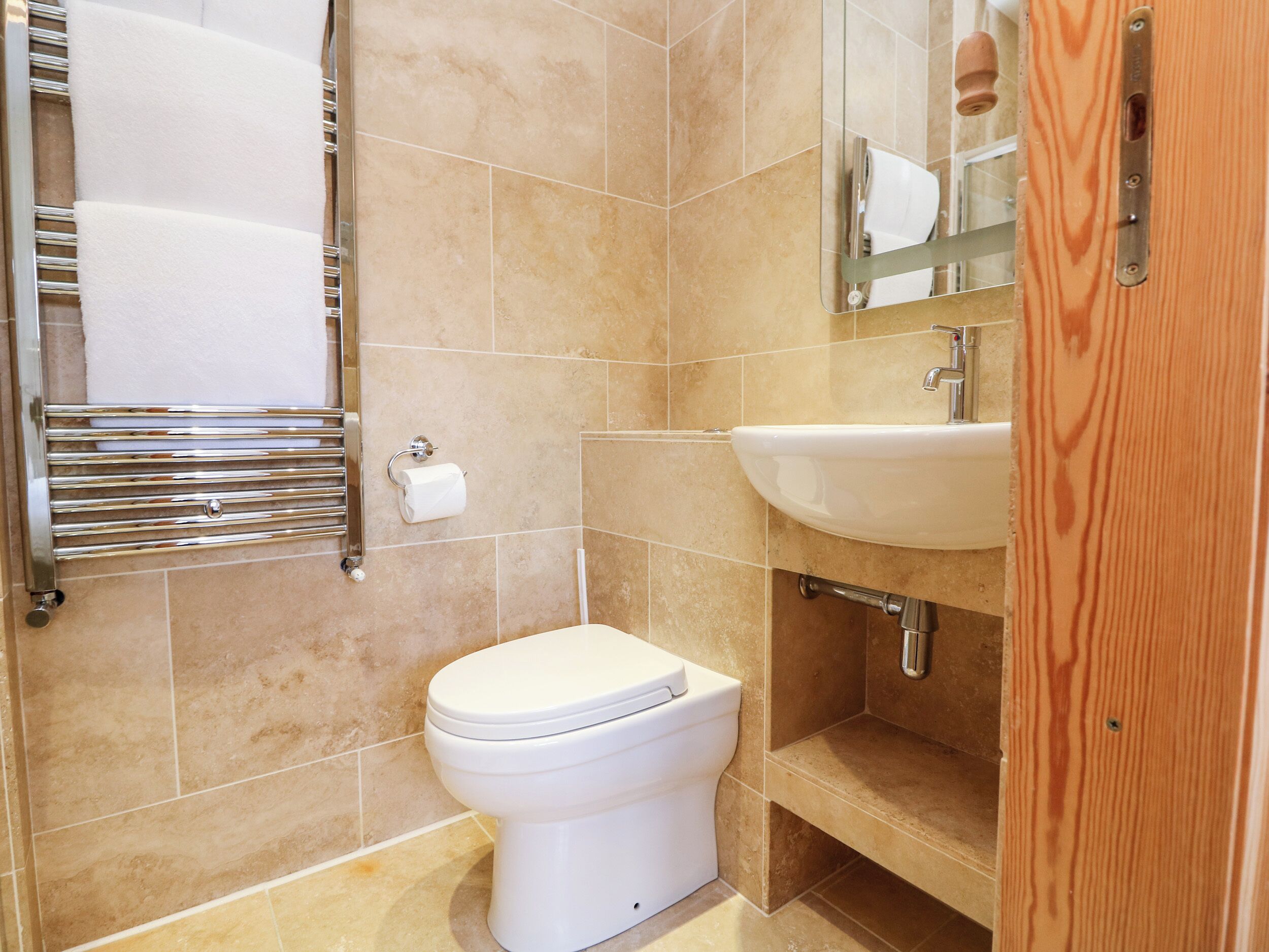 Un baño con inodoro, lavamanos, espejo y toallero.