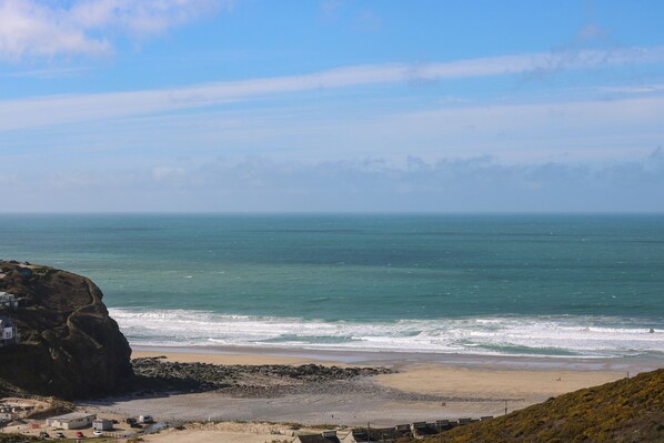 A coastal view with a rocky cliff, beach, and ocean. - Hay Loft (Camborne)