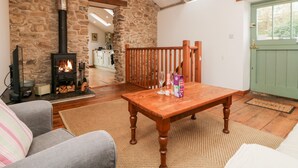Una sala de estar acogedora con una pared de piedra, una mesa de madera y una chimenea.