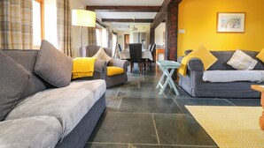 A modern living room with two sofas, a dining table, and a kitchen area in the background. - Marhayes (Camelford)
