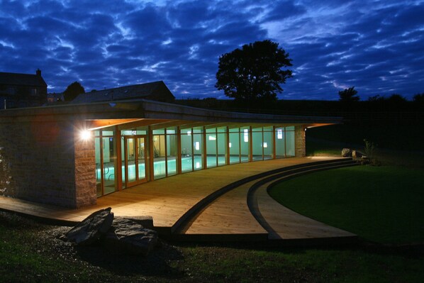 Un bâtiment moderne doté d’une façade en verre incurvé, d’un revêtement extérieur en pierre et d’un hall d’entrée bien éclairé.
