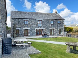 A stone building with a patio area, a wooden table, and a stone bench.