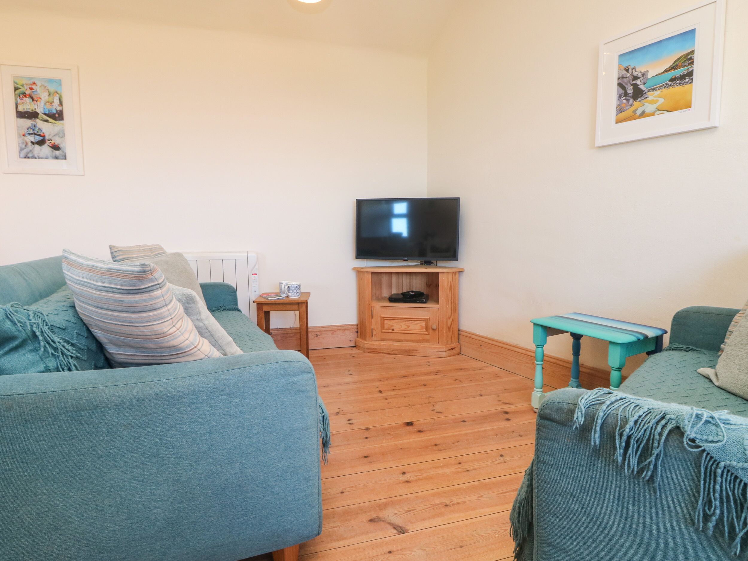 A living room with two sofas, a TV on a wooden stand, and a small table.