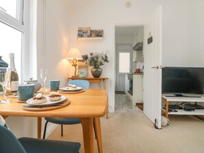 Un comedor con una mesa dispuesta para dos, una lámpara y un cuadro en la pared.