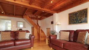 A spacious living room with two leather sofas, a wooden staircase, and a large world map on the wall. - Halvosso (Penryn)