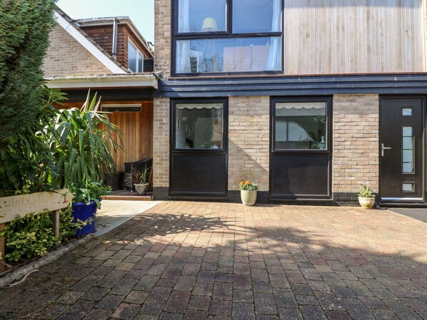 A modern building with a brick facade, large windows, and a paved courtyard. - Little Beach House (St Austell)