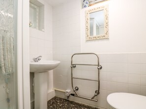 A bathroom with a white sink, a toilet, and a shower area. - Little Beach House (St Austell)