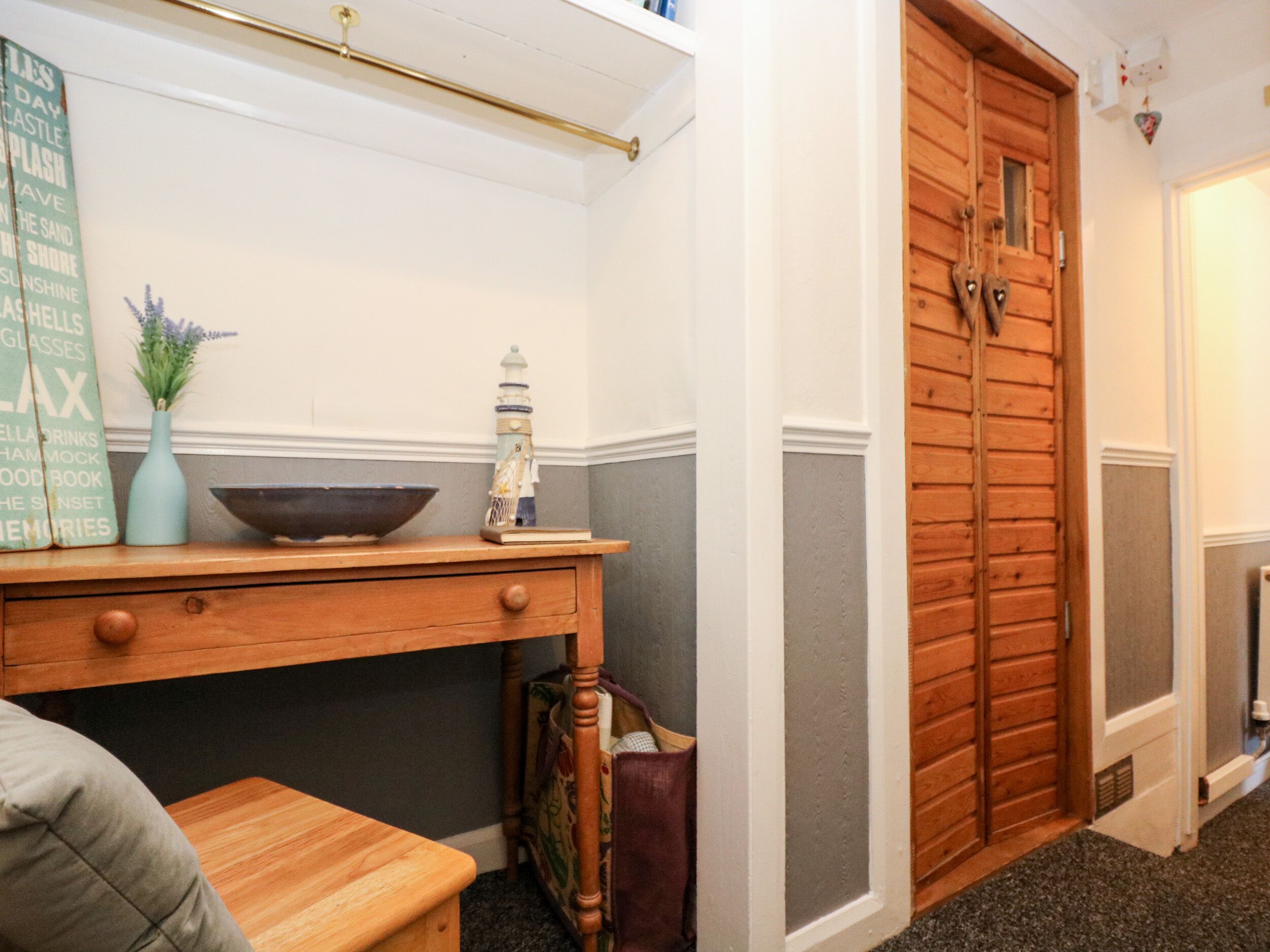 A wooden desk with a bowl and a vase, a small table, and a wooden door with heart-shaped decorations.