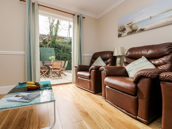 A living room with two brown leather armchairs, a glass coffee table with a book, and a painting on the wall. - Speedwell (St Austell)