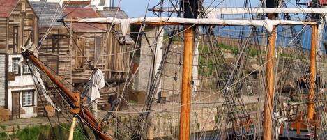 Un barco histórico amarrado en un puerto con un edificio al fondo.