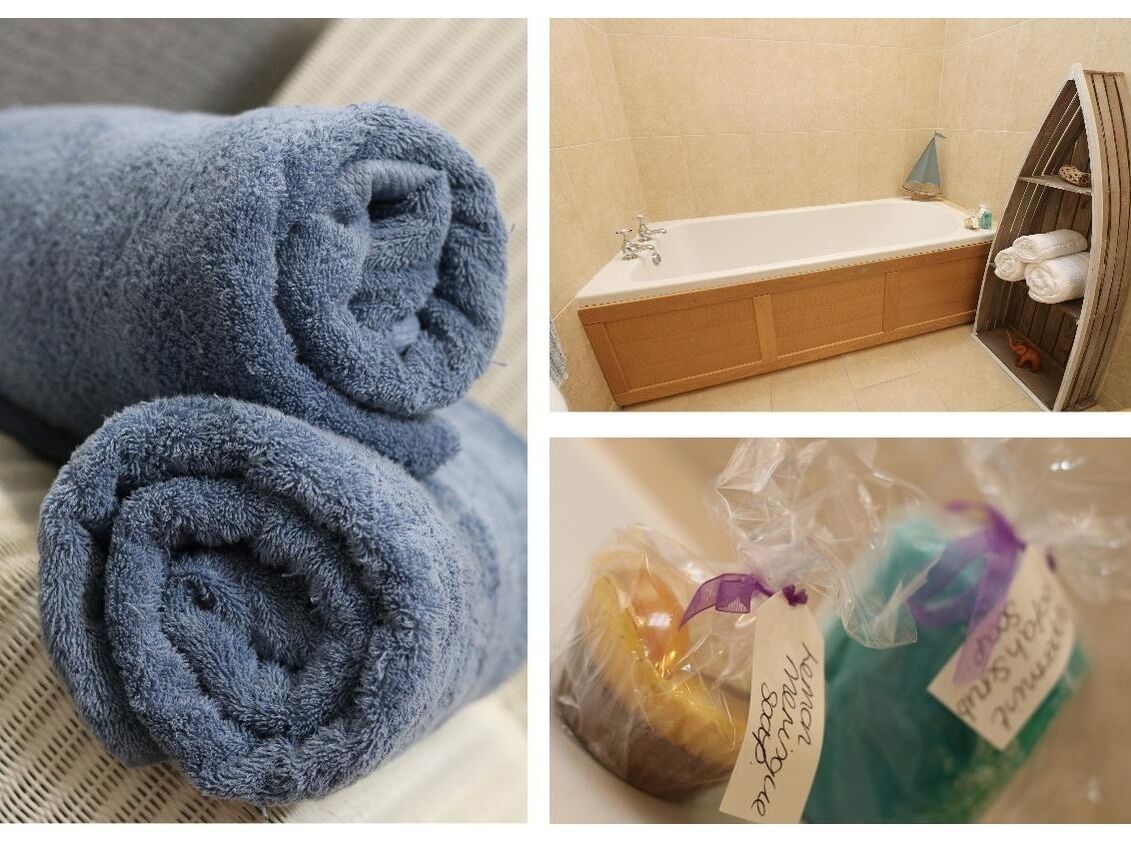A bathroom with a bathtub, a towel rack, and toiletries in plastic bags.