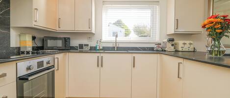 A modern kitchen with white cabinets, a built-in oven, a microwave, and a toaster.