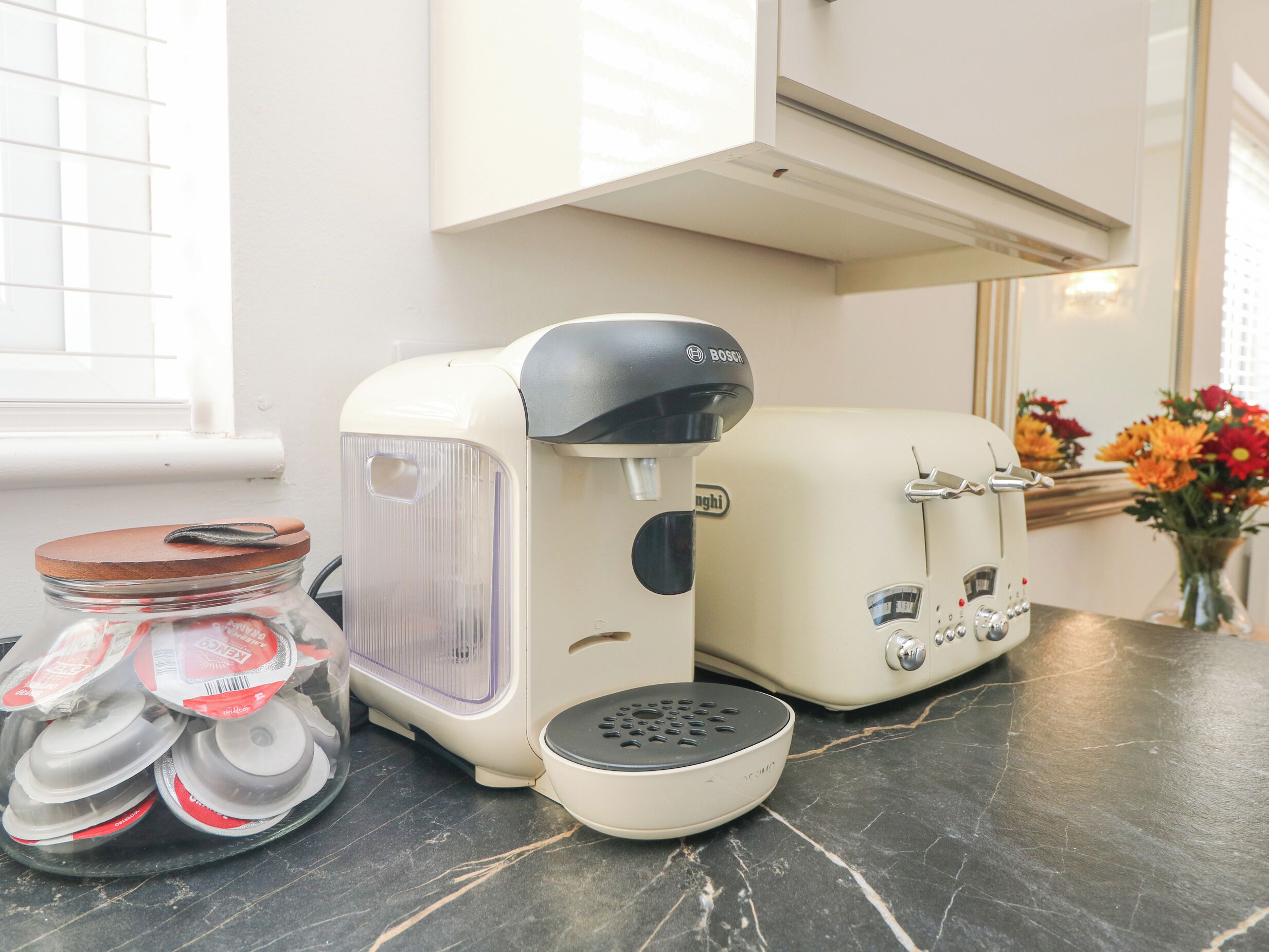 A kitchen with a coffee maker, a toaster, and a jar of tea bags.