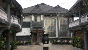 A courtyard with a central fountain, surrounded by a building with a tiled roof and a large window. - Royal Castle Hotel (Lagos)