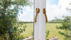 A window with a view of a grassy field and trees. - Bolitho's Retreat (Helston)