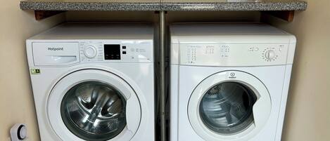 Two front-loading washing machines, a power outlet, and a sign on the wall.