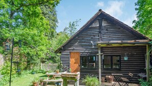 A rustic wooden cabin with a wooden deck, a picnic table, and potted plants. - Endymion (Ringwood)